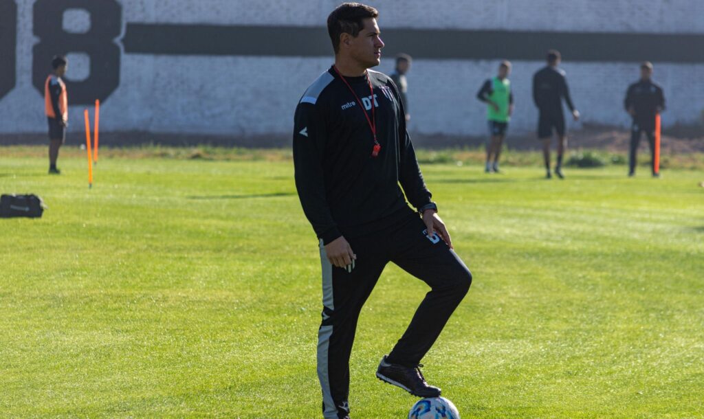 A soccer coach watches on at training.