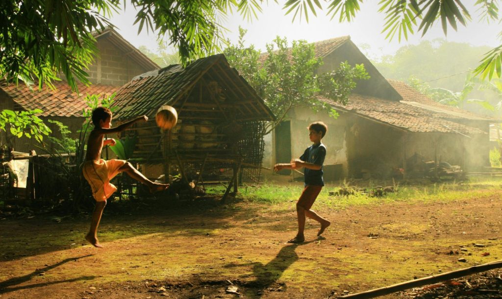 Two boys play outside their rural homes.
