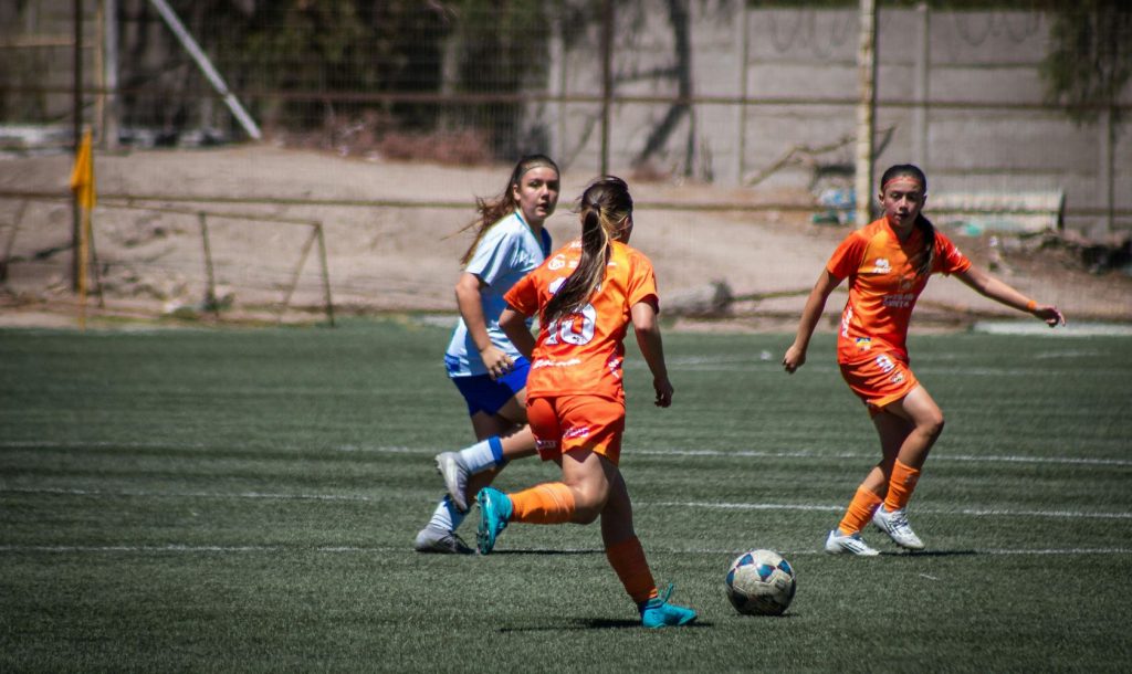 Women play soccer in a competitive match.